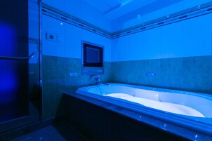 A modern bathroom with a freestanding bathtub, a glass shower enclosure, and a wall-mounted control panel.