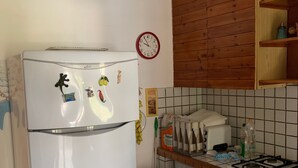 Ett kompakt kök med kylskåp, tvättmaskin, spis och ett träskåp.