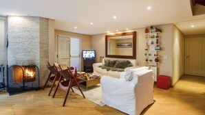 Una sala de estar con chimenea, un sofá, una mesa de centro y una televisión.