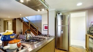 Una cocina moderna con estufa a gas, refrigerador de acero inoxidable y horno empotrado.