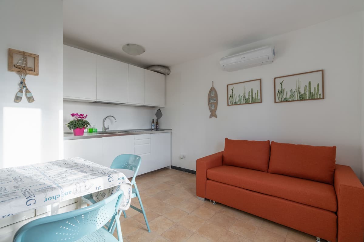A compact living space with a kitchenette, a dining area with a table and chairs, and a sofa.