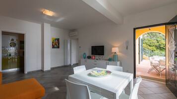 A modern kitchen with a dining area, a TV, and a view of the outdoors.