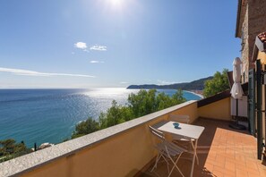 Un balcone con tavolo e sedie affacciato su una vista costiera.
