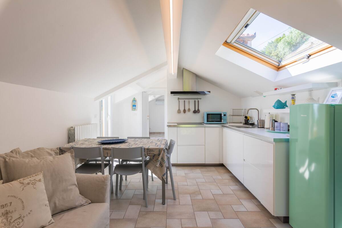 A compact kitchen with a dining area, a green refrigerator, and a skylight.