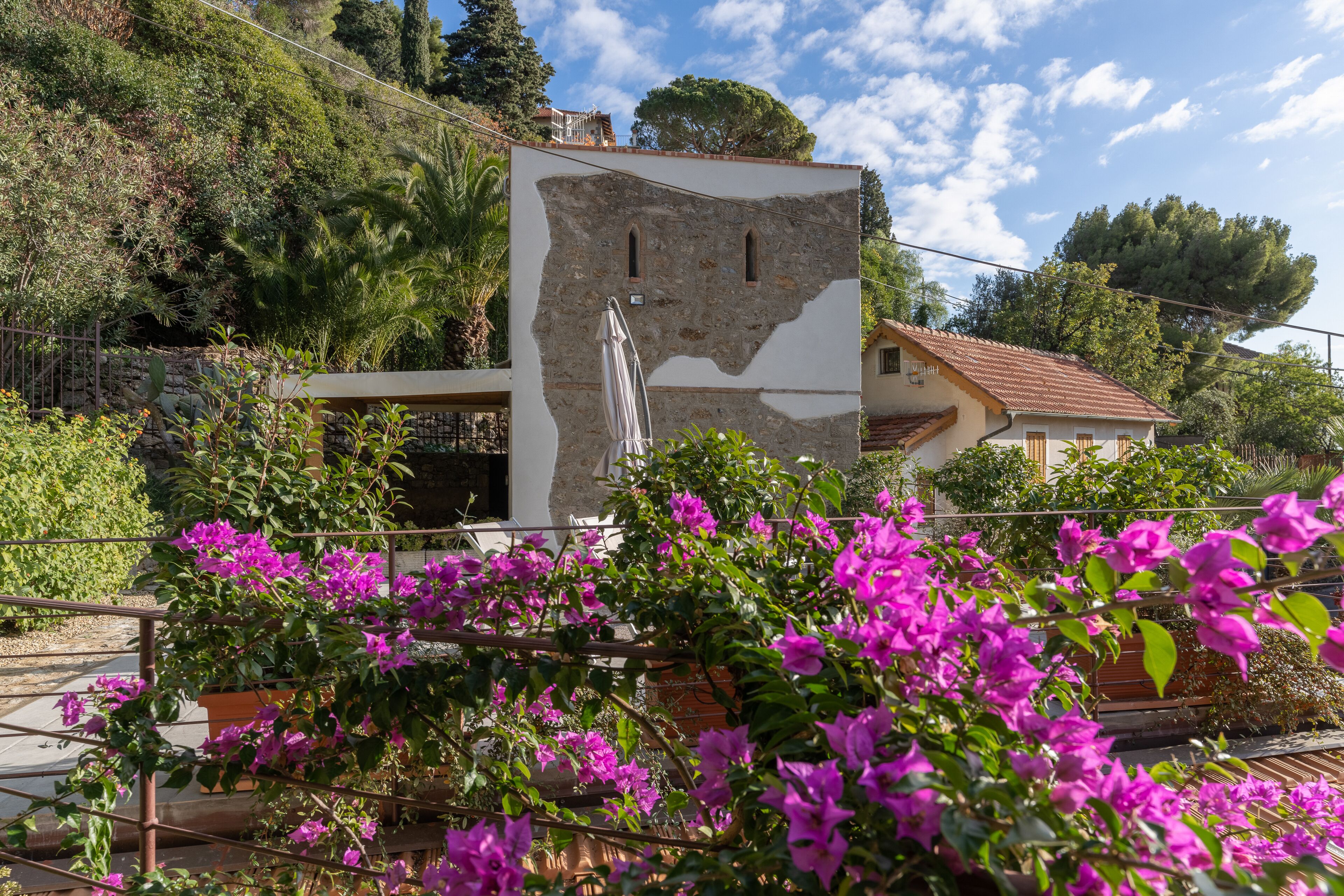 Un edificio con facciata in pietra e un balcone con ombrellone bianco.