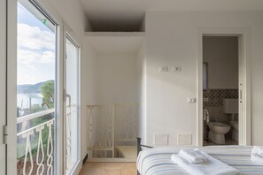 Una camera da letto con letto, bagno e balcone vista mare.