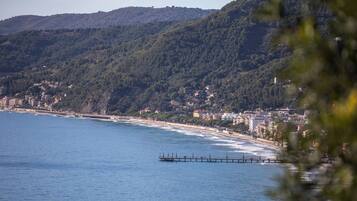 A coastal town with a pier extending into the sea, surrounded by hills and buildings.