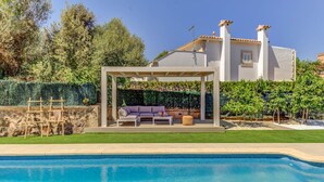 A poolside area with a covered seating area, a stone wall, and a hedge. - Maria Bonaire for eigth people with pool (Alcúdia)