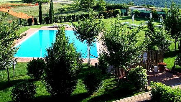 Piscina rodeada de vegetación exuberante y vistas a colinas distantes.
