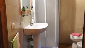 Un baño con lavamanos, espejo y ducha.