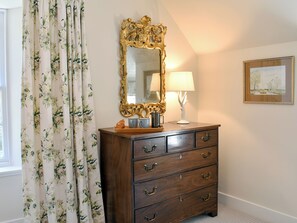 A wooden dresser with drawers, a mirror, and a lamp on top.