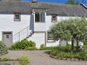 A white building with a grey roof, a staircase leading to a door, and a garden with various plants. - 1 bedroom accommodation in Pitscandly, near Forfar (Pitscandly, near Forfar)