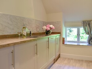 A kitchen with marble backsplash, a window with curtains, and a vase with flowers on the counter.