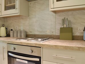 A kitchen with a built-in oven, a coffee maker, and storage containers. - 1 bedroom accommodation in Pitscandly, near Forfar (Pitscandly, near Forfar)