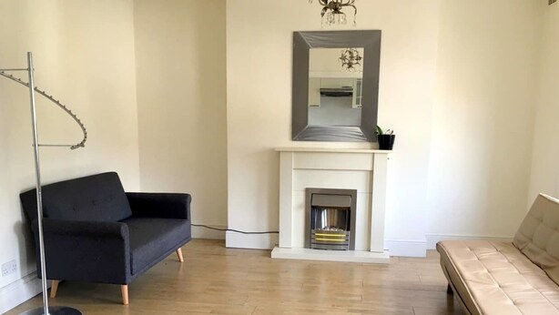 A living room with a black sofa, a beige sofa, a floor lamp, and a fireplace. - Aparthotel Crystal Palace (London)
