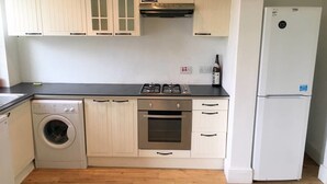 A kitchen with a washing machine, oven, stove, and a refrigerator. - Aparthotel Crystal Palace (London)