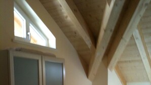 Et værelse med hvælvet loft, træbjælker, en stor garderobe og en seng.