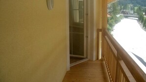 En træbalkon med en glasdør, der fører ind i et rum.