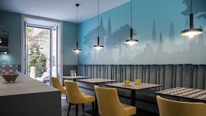 Un restaurante con sillas amarillas, mesas a cuadros y un mural de árboles en la pared.