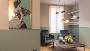 Una sala de estar moderna con un diseño minimalista, que incluye un sofá gris, una mesa de centro con objetos decorativos y un cuadro abstracto grande en la pared.