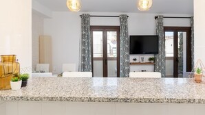 Eine moderne Küche mit Granit-Arbeitsplatten, einem eingebauten Backofen und einem Flachbildfernseher, der über der Spüle angebracht ist.