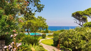 Un jardín con piscina, árboles y vista al mar.