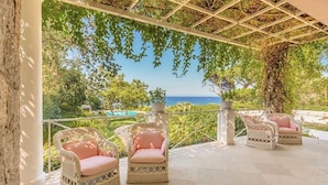 Un espacio de estar al aire libre cubierto con sillas de mimbre y una pérgola.