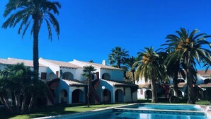 A pool surrounded by palm trees and a building with arched windows and a tiled roof. - Denia beach, ideal for families (Dénia)