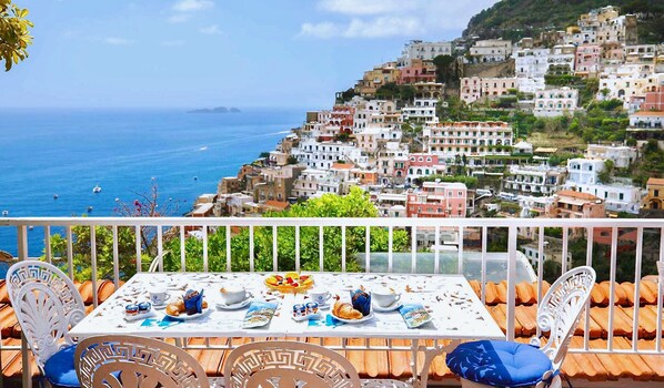 A table set for breakfast with a view of a coastal town and the sea. - IL GIARDINO DI POSITANO (Positano)