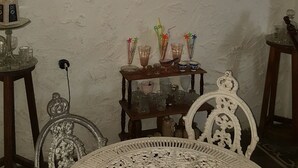 Ein Zimmer mit rundem Tisch, Stühlen und einer Vitrine mit Gläsern.