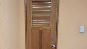 Eine Holztür mit Metallgriff und ein kleiner Podest, der zu einem gefliesten Boden führt.