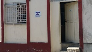 Ein Gebäude mit zwei Türen, eine davon mit einem Schild, das auf eine Abgrenzung hinweist, und einem Fenster mit Gitterstäben.