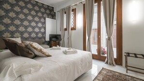 Un dormitorio con una cama grande, televisión y vistas al exterior a través de un ventanal corredero.