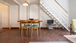 A dining area with a table and chairs, a television, and a staircase. - Cozy and modern studio apartment by Mmega (Florence)