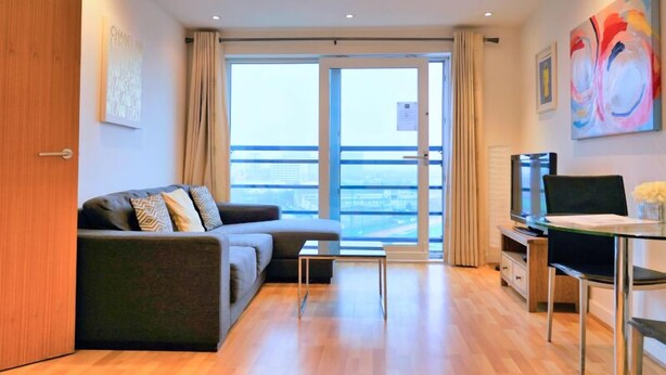 Ein modernes Wohnzimmer mit Sofa, Fernseher und Essbereich.