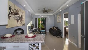 A modern kitchen with granite countertops, a ceiling fan, and a dining area with a table and chairs. - Barri Vacation Home (Kingston)