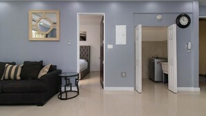 A modern living room with a black sofa, a small round table, and a mirror on the wall. - Barri Vacation Home (Kingston)