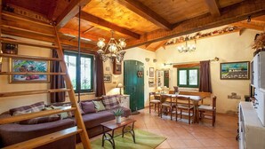 A cozy living room with a sofa, a dining table, and a staircase. - Holiday house Jano in Makarska, jacuzzi (Makarska)