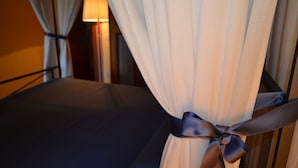 A hotel room with a bed, curtains tied with a ribbon, and a lamp in the background. - Situated inside olive oil farm, Altabina enjoys a panoramic position over the valley and the large h (Lamporecchio)