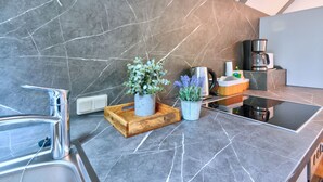 Een moderne keuken met een marmeren achterwand, roestvrijstalen apparatuur en een houten dienblad met potplanten.