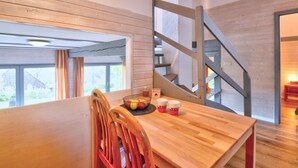Een moderne keuken met een houten tafel, stoelen en een mand met fruit.