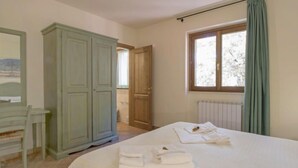 Une chambre à coucher avec un lit, une armoire, une fenêtre avec des rideaux et un radiateur.
