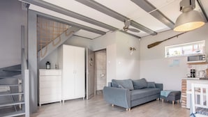 A modern living space with a grey sofa, white cabinets, and a staircase.