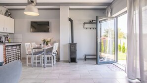 A modern living room with a dining area, a fireplace, and a large sliding glass door to a garden.