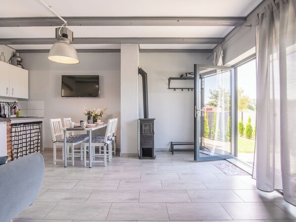 A modern living room with a dining area, a fireplace, and a large sliding glass door to a garden.