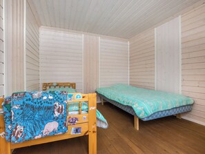 A room with two wooden beds, one with a blue blanket and the other with a green one.