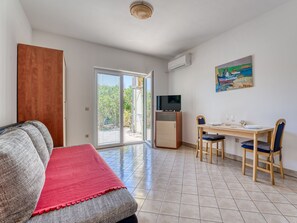 A room with a sofa, a dining table with chairs, a TV, and a painting on the wall. - Balorda by Interhome (Krk/Pinezici)