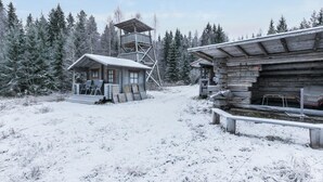 En rustik hytte med træfacade, en lille veranda og et trætårn.