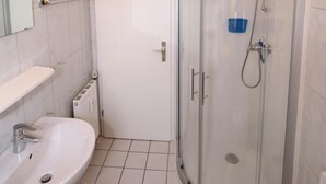 Une salle de bain avec une douche à parois de verre, un lavabo blanc et un miroir.