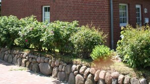Une maison en briques rouges, avec un toit en pente, un mur en pierre et une allée pavée.